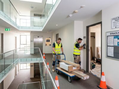 Two tradesmen performing renovation work in a strata complex.